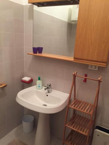 La salle de bains est pourvue d'un lavabo blanc et d'une étagère en bois. dans l'établissement Casa Mia, à Lurisia