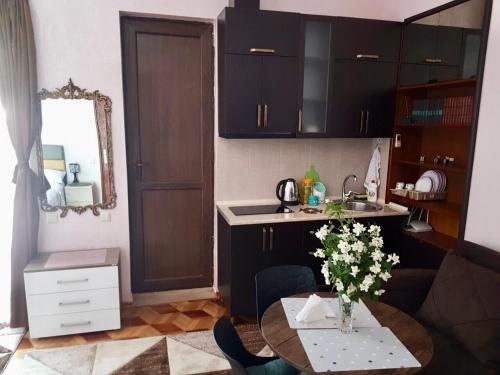 a kitchen with black cabinets and a table with flowers at Sweet Home at Ninoshvili 3 in Batumi
