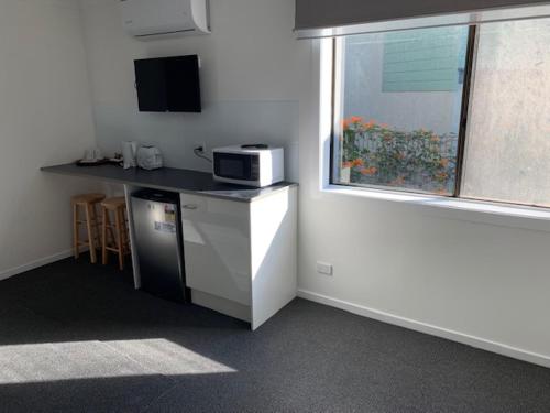 a small kitchen with a microwave and a window at Huskisson Beach Escape in Huskisson