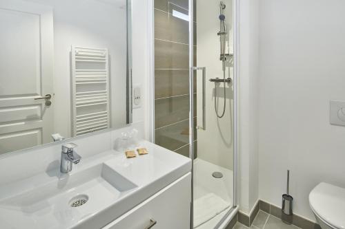 a white bathroom with a sink and a shower at Résidence Vacances Bleues Les Coteaux de Jonzac in Jonzac