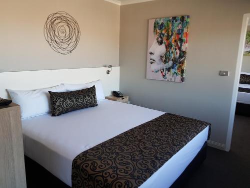 a hotel room with a bed and a painting on the wall at Burnie Central Townhouse Hotel in Burnie