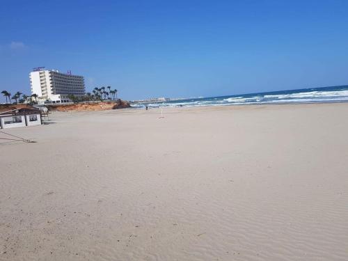 a sandy beach with a building and the ocean at Casa La Florida in Orihuela