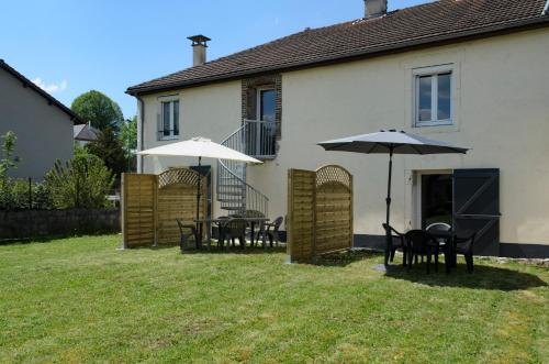 a patio with tables and umbrellas in a yard at L'Orée des Lacs (Appartement n°1) in Pont-de-Poitte