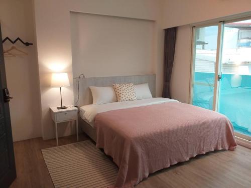 una camera da letto con un letto e una grande finestra di Next door of No 7 Youheng B&B a Città di Hualien