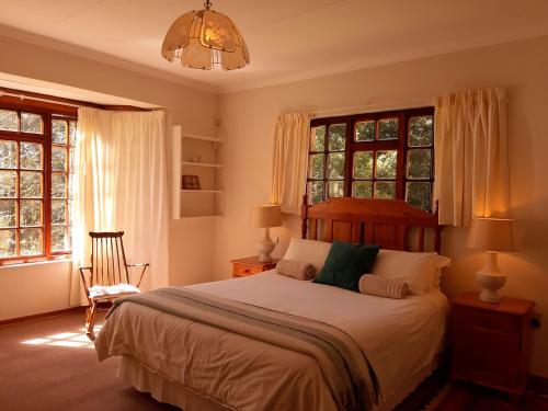 una camera da letto con letto, finestre e lampadario a braccio di Crane Cottage a Dullstroom