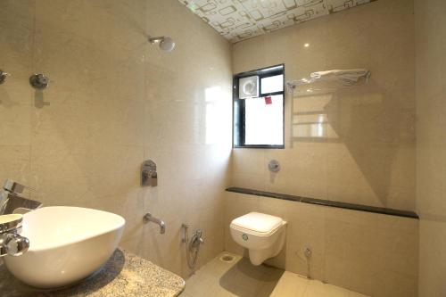a bathroom with a sink and a toilet and a window at Hotel Shivam in Pune