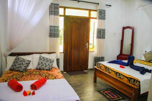 a bedroom with two beds with red pillows and a mirror at Amba Sewana Homestay in Sigiriya