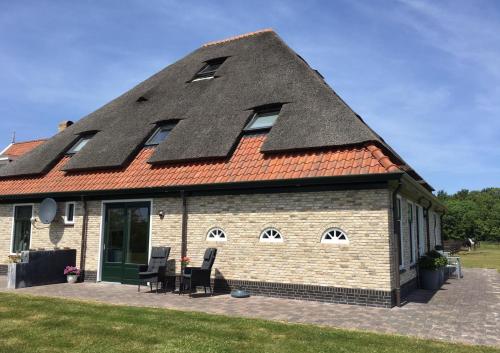 a house with a pitched roof with windows and chairs at 't lant van Texsel in De Koog