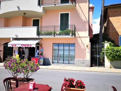 ein rosafarbenes Gebäude mit einem Tisch und Blumen auf der Straße in der Unterkunft La Palma vacanze in riva al mare in Diano Marina