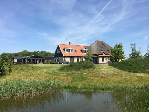a large house on a field next to a body of water at 't lant van Texsel in De Koog