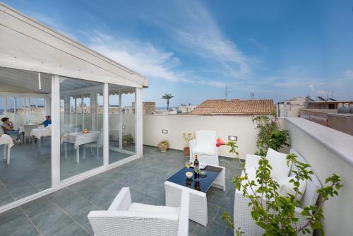 a balcony with white chairs and tables on a building at Hotel Biancolilla in San Vito lo Capo