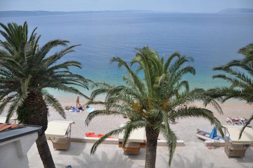 a view of a beach with palm trees and the ocean at Villa DELFINA in Podgora