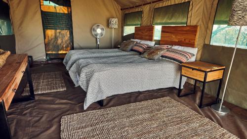 a bedroom with a bed and a table with a lamp at ZuriCamp - Tent Amani in Tsumeb
