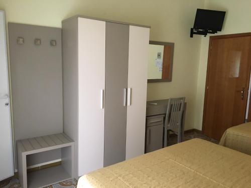 a bedroom with a bed and a cabinet and a desk at Hotel Laila in Cesenatico