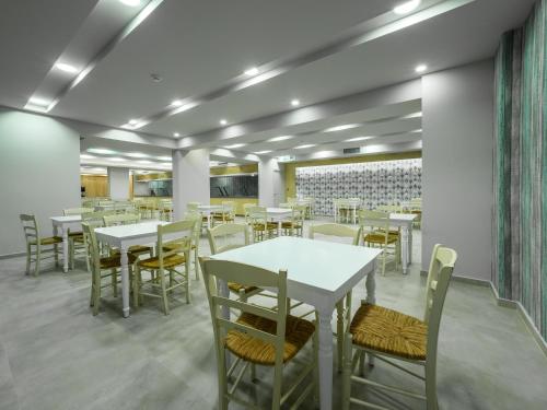 a dining room with white tables and chairs at Paradise Resort in Finikounta