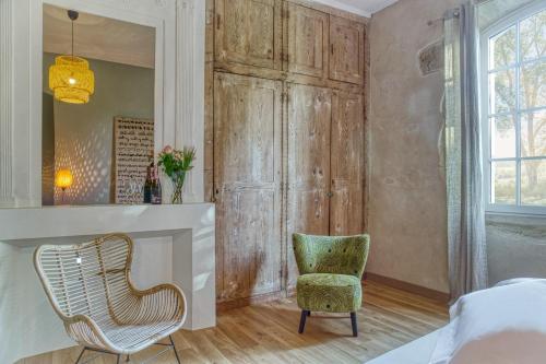 een slaapkamer met een stoel, een bed en een spiegel bij Le Château de Camille in Saint-Jean-le-Comtal