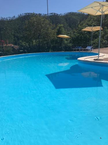 a large blue swimming pool with umbrellas at Antiche Terre Hotel & Relax in Pignone