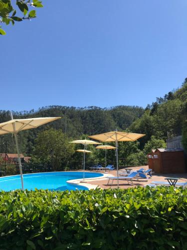 a swimming pool with umbrellas and lounge chairs at Antiche Terre Hotel & Relax in Pignone