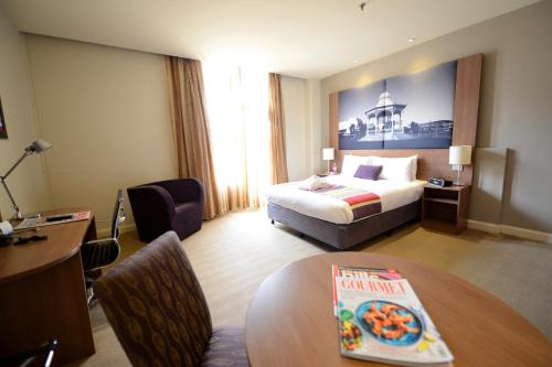 a hotel room with a bed and a table at Grosvenor Hotel Adelaide by Accor in Adelaide