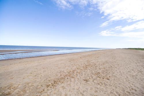 a beach with footprints in the sand and the water at Skegness Holiday Cottages in Skegness
