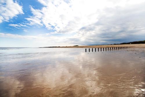 a beach with the reflection of the sky in the water at Skegness Holiday Cottages in Skegness