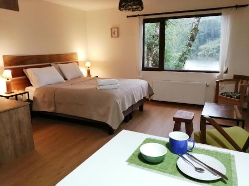 ein Schlafzimmer mit einem Bett und einem großen Fenster in der Unterkunft Casa Río Vivo in Valdivia