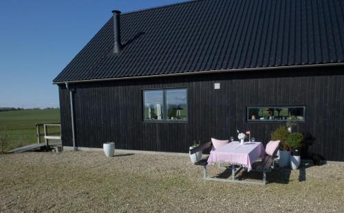 a black building with a table and chairs in front of it at B&B Hesselbjerg in Hesselbjerg
