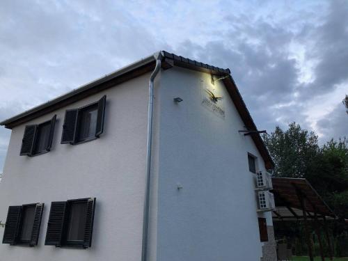 a white building with black shuttered windows on it at Sirály Apartman in Hajdúnánás