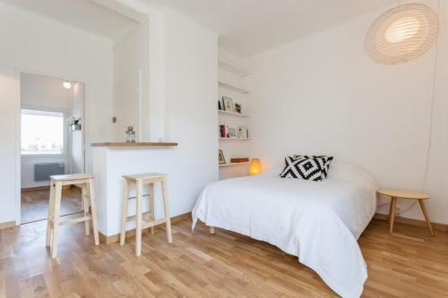 - une chambre blanche avec un lit, une table et un tabouret dans l'établissement Le Minot, à Marseille