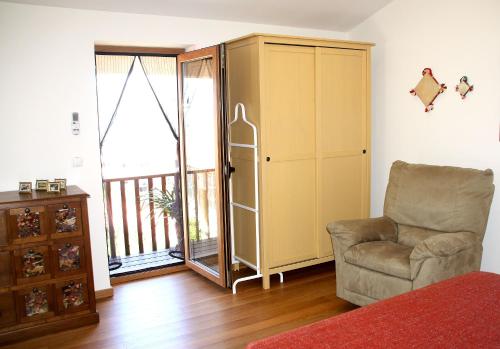 ein Wohnzimmer mit einem Stuhl, einem Schrank und einem Balkon in der Unterkunft Casa da Eira Velha in Vale de Cambra