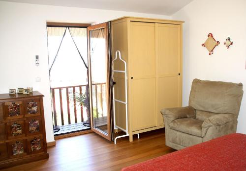 a living room with a chair and a cabinet and a balcony at Casa da Eira Velha in Vale de Cambra