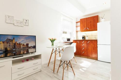 a kitchen with a tv and a table with white chairs at Apartments Gdańsk Dworska by Renters in Gdańsk