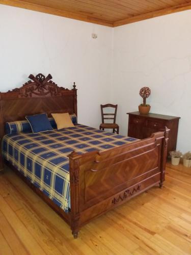 a bedroom with a wooden bed with a blue and white comforter at A casa da serra - alojamento local in Casal Velho