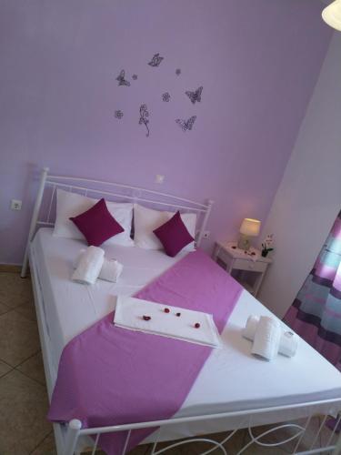 sypialnia z białym łóżkiem z fioletowymi prześcieradłami i motylami na ścianie w obiekcie Nikoletta Rooms w mieście Parikia