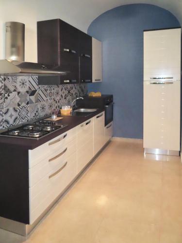 a kitchen with white cabinets and a stove top oven at Casa Vacanze Donna Lucia in Scoglitti