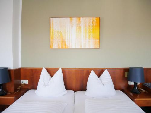 two beds with white pillows in a hotel room at Stadthaus Valentin in Altötting