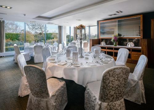 Moyvally的住宿－莫伊谷高爾夫度假酒店，用餐室配有带白色椅子和桌子的桌子