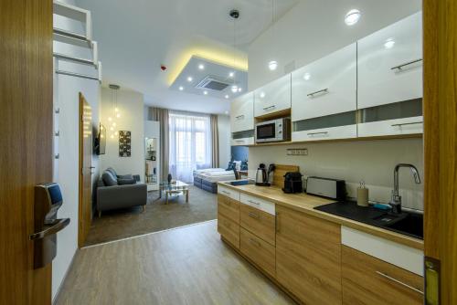 a kitchen with white cabinets and a living room at Karoly Corner Residences in Budapest