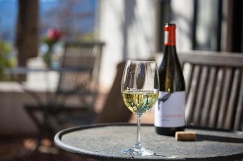 a glass of white wine next to a bottle of wine at Bartinney Private Cellar Banhoek in Stellenbosch