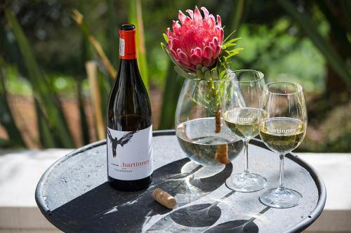 a bottle of wine and two wine glasses on a table at Bartinney Private Cellar Banhoek in Stellenbosch