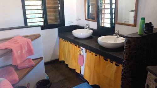 a bathroom with two sinks and two mirrors at JJ ET EUPHRASIE Lodge in Nosy Be