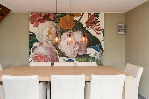 斯哈倫代克的住宿－Vakantiehuizen 7Huizen aan Zee，餐桌、白色椅子和绘画