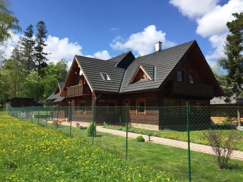a wooden house with a black roof at Villa Milan in Tatranská Lomnica