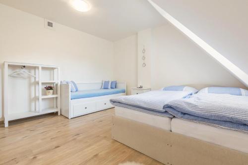 a white bedroom with two beds and a bench at Vinařství Fiamoli in Vracov