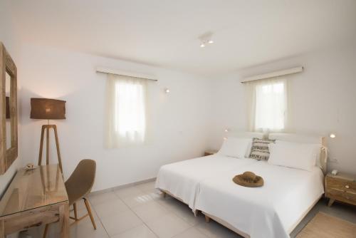 a white bedroom with a bed with a hat on it at Hotel Charissi in Mýkonos City
