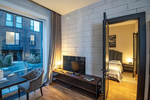 a living room with a television and a bedroom at Warm House Apart Hotel in Almaty