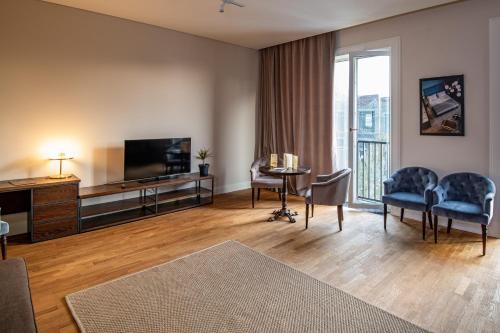 a living room with a television and a table and chairs at Warm House Apart Hotel in Almaty