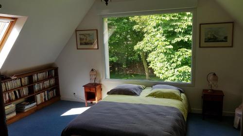 a bedroom with a bed and a large window at L Eskemm in Plouaret