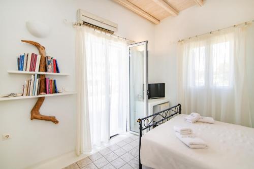 Un dormitorio blanco con una cama y una ventana. en Vincenzo Family Rooms, en Tinos