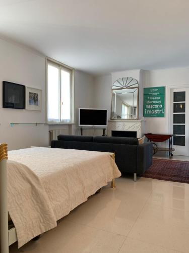 a bedroom with a bed and a couch and a television at Masnadieri 18 in Parma